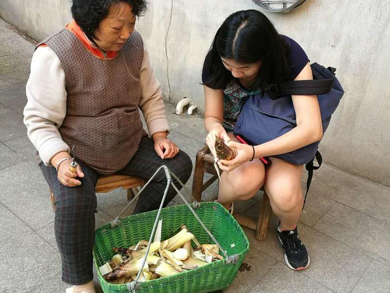 A student handles bamboo that an older woman has shucked